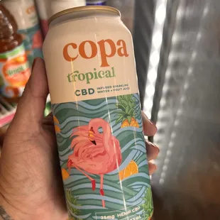 a person holding a can of cola tropical