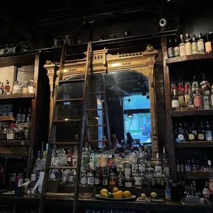 a ladder leaning against a wall of liquor bottles