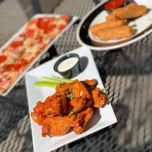 a plate of chicken wings and a plate of pizza