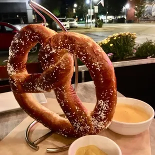 a large pretzel and two small bowls of mustard