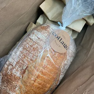 Fresh loaf of country sourdough bread and other baked goodies tucked beneath it.