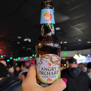 a hand holding a bottle of angry orchard hard cid