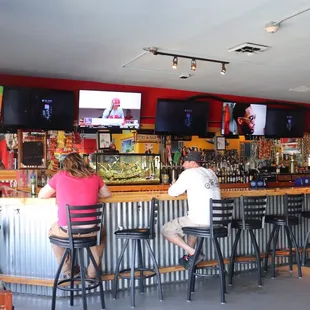 people sitting at the bar watching tvs