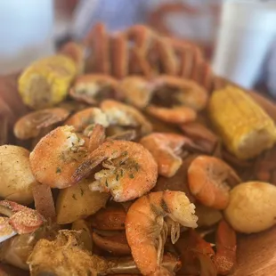 a plate of shrimp, potatoes, corn, and potatoes