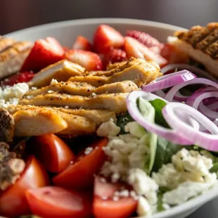 Strawberry Chicken salad made with fresh seasoned grilled chicken, feta cheese, candied pecans, onion, tomato, and cucumbers.