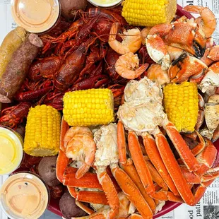a platter of crab legs, corn, potatoes, and corn on the cob