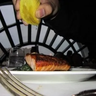 Squeezing lemon on salmon filet