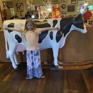 a young girl standing in front of a cow statue
