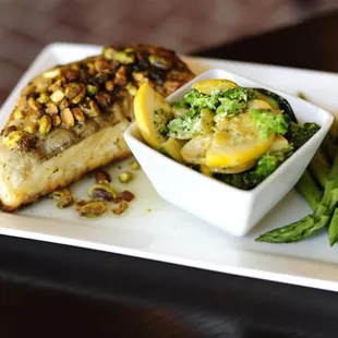 Grilled Swordfish Loin topped with crushed pistachios and drizzled with a lemon and parsley infused olive oil. Served with sides