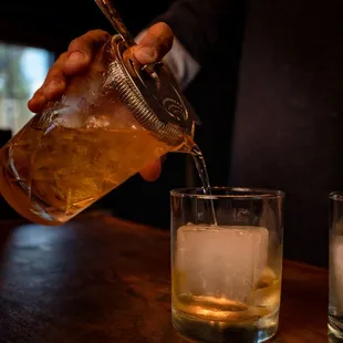 a person pouring a drink into a glass