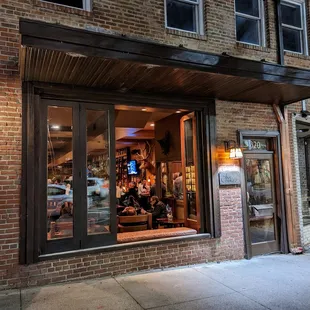 Outside. Storefront at night. Low key. The Crunkleton is located between Tropical Smoothie Cafe (The Book Shop) and Tea Hill (Cha House).