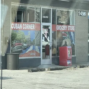 a storefront with a red trash can in front of it
