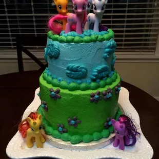 a three tiered cake with little pony figures on top