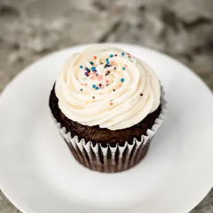 Custom Chocolate cupcake with vanilla frosting and sprinkles.