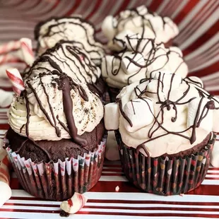 three chocolate cupcakes with white frosting and chocolate drizzles