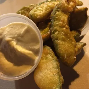 a plate of fried pickles and a bowl of dip