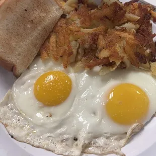two eggs sunny side up with american fries and white toast