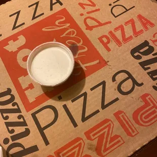 a cup of milk on a pizza box
