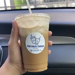 a hand holding a cup of iced coffee