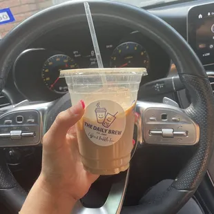 a hand holding a cup of iced coffee