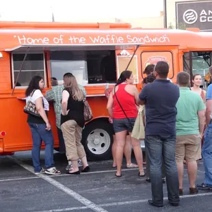 a line of people waiting to get food from a food truck