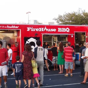 a crowd of people standing in line at the food truck