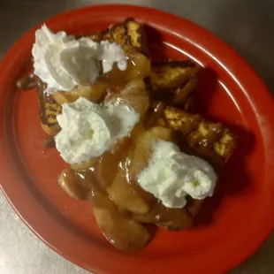 a plate of french toast with whipped cream and caramel sauce