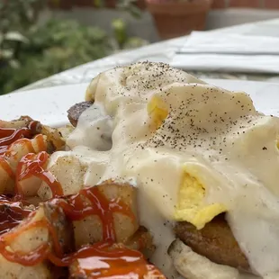 Biscuits and gravy with sausage and home fries.