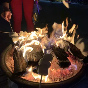 a person roasting marshmallows over a fire pit