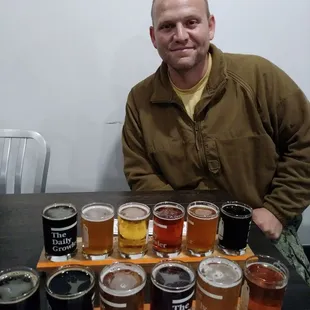 a man sitting at a table with a variety of beers