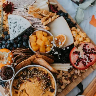 a platter of cheese, fruit, and crackers
