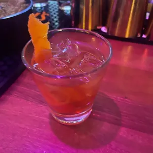 a drink in a glass with an orange garnish