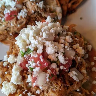 CHICKEN TINGA TOSTADAS (8)  Chicken tinga tostadas-cooked in tomato &amp; adobo sauce, creamy avocado crema, cotija cheese &amp; pico.