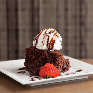 a piece of chocolate cake with ice cream and strawberries