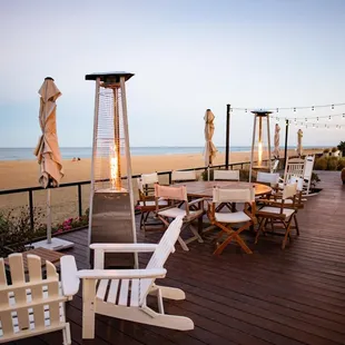 tables and chairs on a deck overlooking the beach