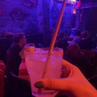 a person holding a drink in front of a crowd