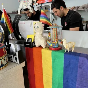 a man behind a counter with a rainbow flag