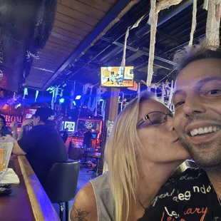 a man and a woman kissing at a bar