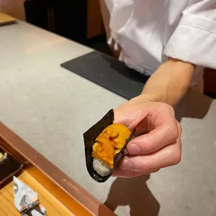 a person holding a piece of sushi