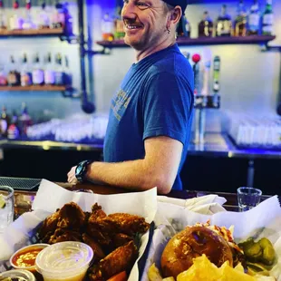 a man standing behind a bar filled with food