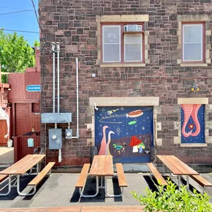a row of picnic tables in front of a brick building