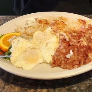 a plate of eggs, hash browns, and orange slices