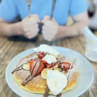 a plate of pancakes with strawberries and bananas