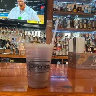 a drink in a plastic cup on a bar