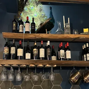 a shelf of wine bottles and wine glasses