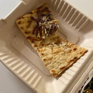 a slice of pizza in a styrofoam container