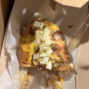 Half of the chili cheese dog w/ onions on top