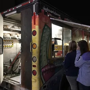 two women standing in front of a food truck