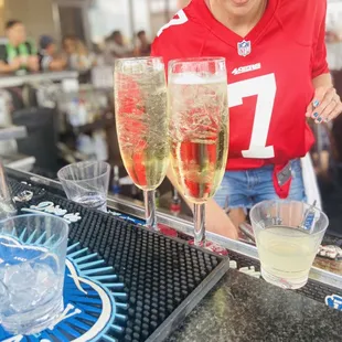 a woman in a red jersey and glasses of champagne
