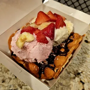 Strawberry and vanilla ice cream with chocolate cream, bananas, strawberries, and waffle